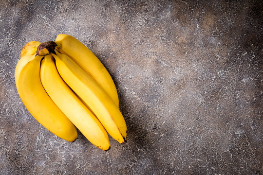 Bananas on concrete background. Fresh yellow banana on dark stone table. Top view, copy space