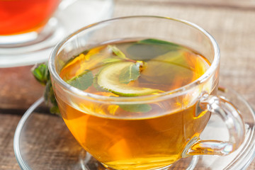cup of black tea with mint leaves on a wooden table