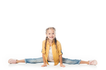 Fototapeta na wymiar smiling little kid stretching, doing split and looking at camera isolated on white