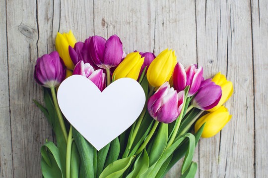 Greeting card - Pink and yellow tulips on a wooden background