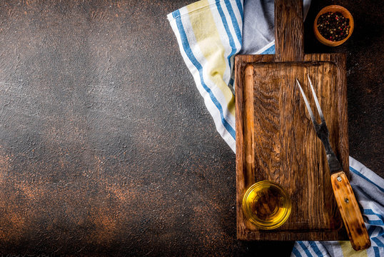 Old cutting board with Carving Fork, herb and spices on dark wooden background copy space top view