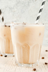 Summer cold Iced coffee frappe with milk and ice cubes, light concrete background copy space