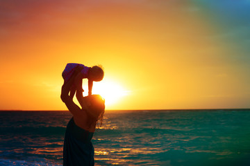 happy mother and baby daughter play at sunset