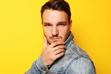 Portrait of a handsome young man, fashion model. Posing over yellow wall. Lifestyle and fashion concept.