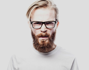 Portrait of a young bearded man frowning. Studio shot.