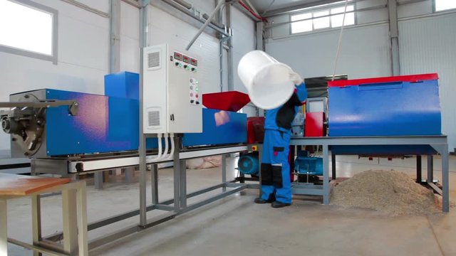 Worker loads sliced plastic in automated plastic recycling machine