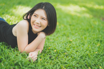 Naklejka na ściany i meble beautiful and pretty asian woman in casual dress relax and happiness break on green grass fireld in garden