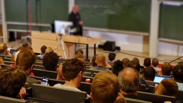 Professor or teacher delivers a lecture college to a large audience of students 