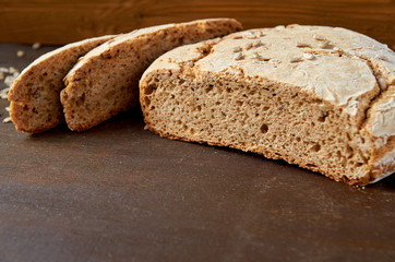 Homemade sliced appetizing fresh bread on the wooden background ready to eat. Just baked tasty bread on the brown table with free copy space. Side view