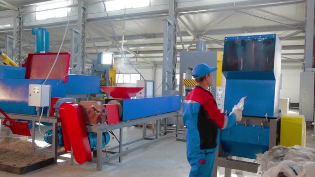 Worker loads sorted plastic in automated plastic recycling machine