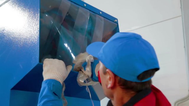 Worker loads sorted plastic in automated plastic recycling machine