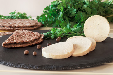 Dietary homemade chicken mortadella with spices on slate board. Protein rye multicereal flatbread. White background.