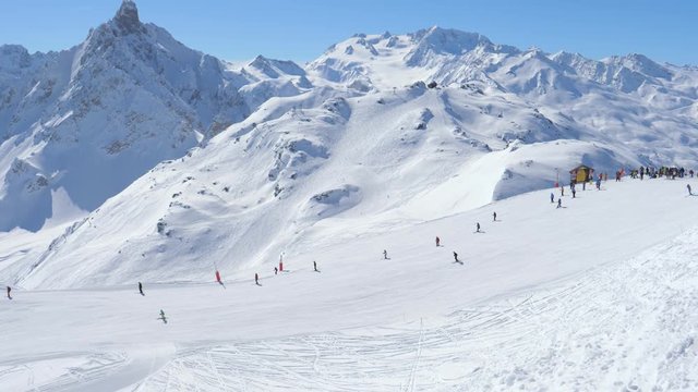 Typical sunny day in the mountains at a ski resort, many skiers on the slope