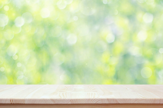 Empty wooden countertop on blurred spring background with bokeh.