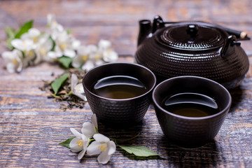 Tea cup, tea pot,  jasmine flowers, green tea, mint, on wooden background