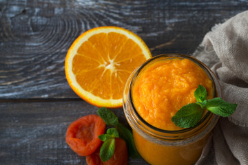 Healthy raw orange jam with dried apricots in a glass jar with cookies on a wooden table. diet food. selective focus. free space. rustic style