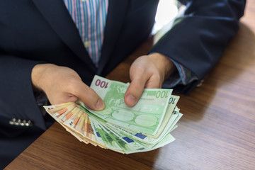 Hand in suit holding fifty and hundred euro bill notes