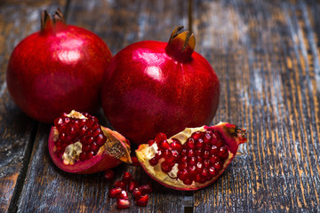 Garnet red, ripe, juicy, whole and half of a pomegranate, grain, seeds on a wooden background