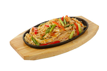 Funchoza, chicken, pork with meat, red pepper and green onions, serving in hot frying pan, on wooden board on white isolated background side view. For the menu, restaurant, bar, cafe
