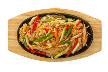 Funchoza, chicken, pork with meat, red pepper and green onions, serving in hot frying pan, on wooden board on white isolated background view from above. For the menu, restaurant, bar, cafe