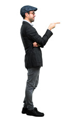 Handsome modern man with beret and glasses pointing finger to the side and presenting a product