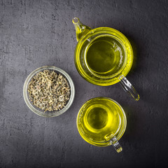 Green tea,brewed in a transparent teapot.Dry tea leaves, dark black background.The view from the top.