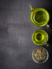 Green tea,brewed in a transparent teapot.Dry tea leaves, dark black background.The view from the top.