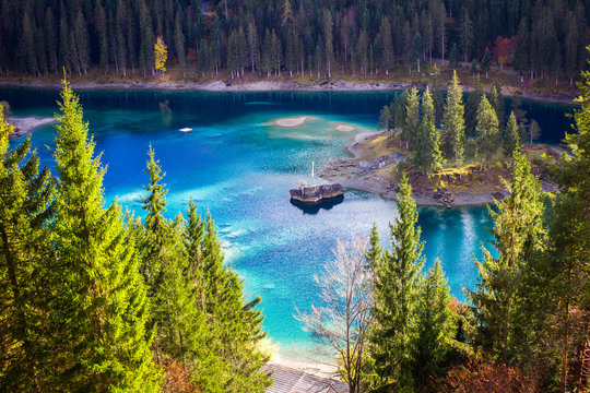 blauer, klarer, sauberer Bergsee Caumasee in Laax, Flims in Graub&uuml;nden in der Schweiz mit einer kleinen Insel aus Stein im See und Wald im Sommer