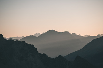 Fototapeta premium Distant mountain silhouette with clear sky and soft light. Toned image, vintage filter, split toning.