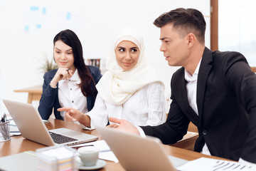 The Arab woman in hijab works in the office together with her colleagues.