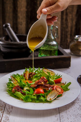 Crispy salad with bacon and cherry on a white plate and sauce