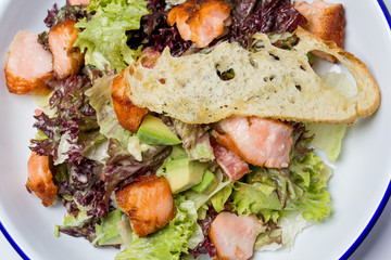 Juicy salad with salmon, salad mix, croutons, Caesar sauce. In a round plate. View from above. Close-up