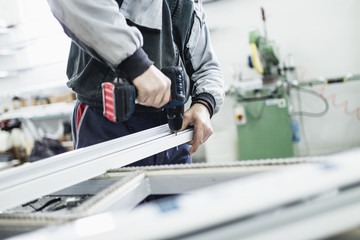 Manual worker assembling PVC doors and windows. Manufacturing jobs. Selective focus. Factory for aluminum and PVC windows and doors production.