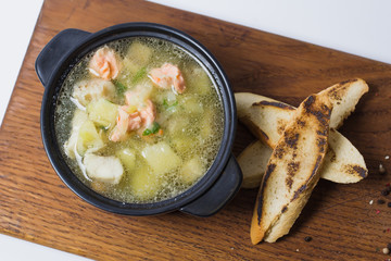 Soup with meat, potatoes and spices. With croutons. On a wooden plaque. View from above. Close-up