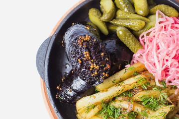 Black pudding with fried potatoes. With marinated cabbage and gherkins. In a frying pan. View from...