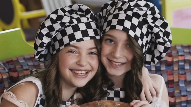 Two young girl with smile presentating a pizza for camera
