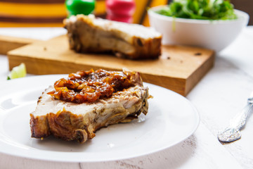Fried piece of pork on a white ceramic plate side view
