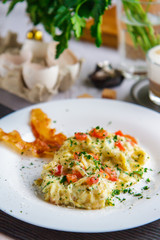 Scramble of eggs and bacon on a white plate close-up