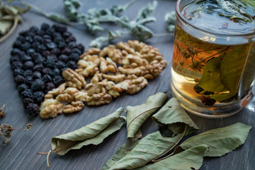 heart of dried cherries nuts and dried leaves of tea , cup of herbal tea on the foreground , side view