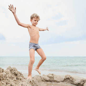 Portrait of healthy little boy playing on the seashore with sand, image with square aspect ratio