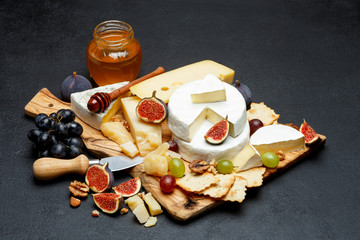 Brie cheese on a wooden Board with fresh figs and grapes