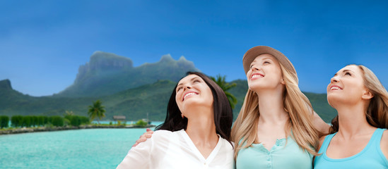 travel, tourism and summer vacation concept - group of happy smiling women or friends over bora...