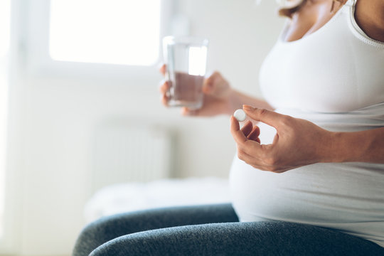 Picture of pregnant woman taking medication pills