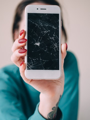 Broken glass screen smartphone in hand, white background