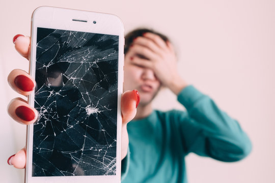 Broken glass screen smartphone in hand of upset girl, white background
