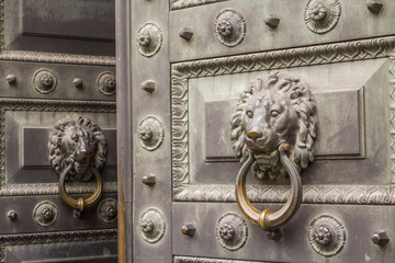 A slightly open antique metal door with a hammerhead door knocker (Приоткрытая старинная металлическая дверь с дверным молотком в виде львиной головы)