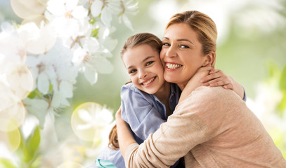 people and family concept - happy smiling mother hugging daughter over cherry blossom background