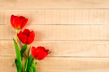 Three red tulips lie on a table