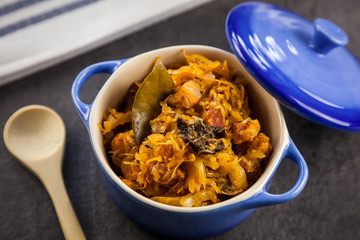 Bigos - a traditional Polish dish with sauerkraut and fresh cabbage with meat, bacon and mushrooms in blue ceramic pot