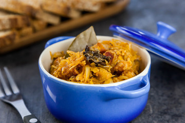 Bigos - a traditional Polish dish with sauerkraut and fresh cabbage with meat, bacon and mushrooms in blue ceramic pot